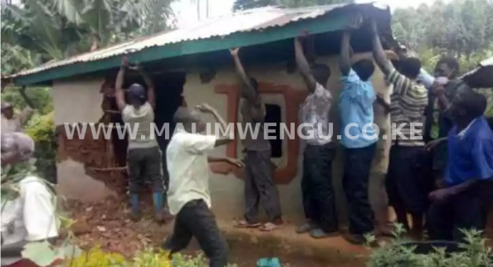 Residents of Kenyoni area bringing down the woman's house after being banished